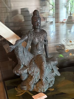 une statue représentant une femme assise sur un rocher, un livre à la main