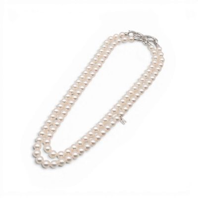 un collier de perles blanches avec un fermoir en argent sur fond blanc