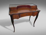 an antique writing desk with a glass top and wooden legs