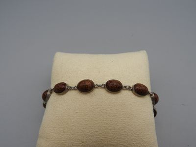 un gros plan d'un bracelet posé sur un oreiller, sur une surface blanche