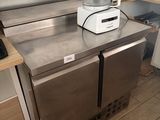un plan de travail en acier inoxydable sur lequel est posé un mixeur, dans une cuisine