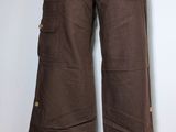 Le pantalon est marron et comporte des boutons ; il est présenté sur un mannequin.