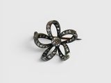 un gros plan d'une broche en forme de fleur en noir et blanc posée sur une surface blanche