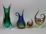 trois vases en verre de couleurs différentes posés l'un à côté de l'autre sur une surface blanche