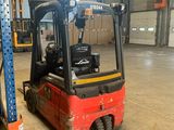 a red forklift in a warehouse with pallets in the background
