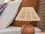 a small table with a lamp on it next to a bed