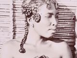 une vieille photo en noir et blanc d'une femme aux cheveux tressés