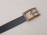 a black belt with a gold buckle on a white surface