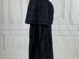une robe noire posée sur un mannequin devant un mur blanc