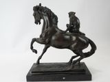 bronze statue of a man riding a horse on a marble base