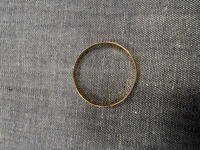 un gros plan d'une bague en or posée sur un tissu noir