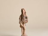 une vieille statue représentant un homme tenant un oiseau, posée sur une surface blanche