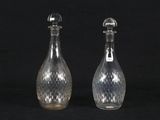 pair of clear glass bottles with silver tops on a black background