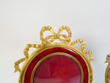 two red and gold picture frames sitting on a table