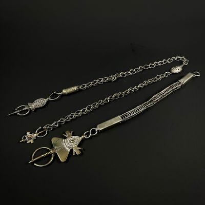 trois colliers en argent avec des breloques et des chaînes sur fond noir