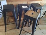 quatre tabourets noirs placés devant un mur en bois