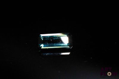 une photo d'une tourmaline verte dans une pièce sombre