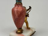 a pink vase on a marble base with a statue on the base