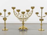 three brass candelabs with ornate designs on each of them