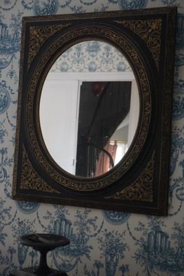 un miroir accroché au mur au-dessus d'une chaise dans une pièce
