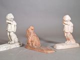 three small statues of a boy and a girl on a surfboard