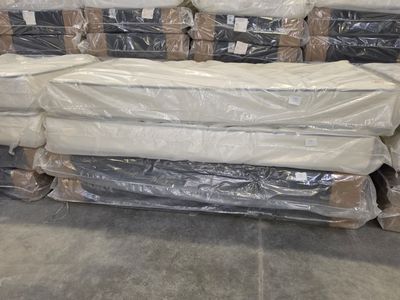 a lot of mattresses stacked on top of each other in a warehouse