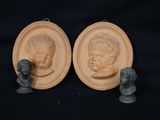 pair of bronze busts of a boy and a girl on a black background