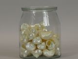 a glass jar filled with small white spiral beads