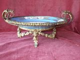 une assiette bleue et dorée posée sur un socle, sur un tissu rouge