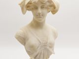 un buste en marbre blanc représentant une femme coiffée d'un chapeau