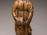 une statue en bois représentant un homme coiffé d'un chapeau et vêtu d'une robe