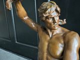 une statue en bronze représentant un homme tenant un couteau à la main