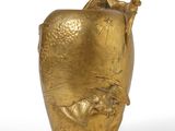 a gold vase that is sitting on a white surface