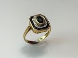 a close up of a gold ring with a black and white stone