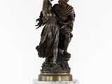 une statue en bronze représentant une femme tenant un enfant dans ses bras, posée sur un socle en marbre