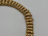 a close up of a gold necklace on a white surface