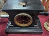 une horloge noire posée sur une table recouverte d'une nappe rouge