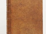 an old book with a brown cover sitting on a white surface