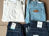 trois paires de jeans pour homme sont posées sur une boîte en carton
