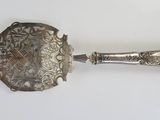 an old silver spoon with a handle on a white surface