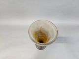 a white vase with a brown liquid inside of it
