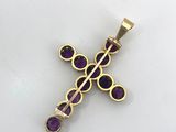a gold cross pendant with amethtites and purple stones