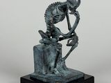 statue en bronze représentant un squelette assis sur un rocher, la tête entre les mains