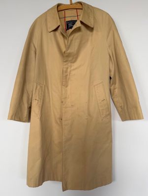 a tan trench coat hanging on a hanger on a wall