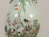 a vase with a painting on it sitting on a table