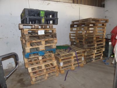 Plusieurs palettes de vin sont empilées les unes sur les autres dans un garage