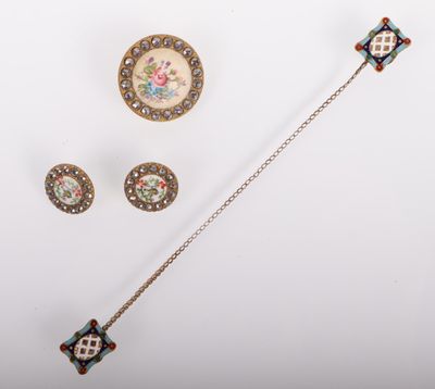 a close up of a necklace, brooch, and earrings on a white surface
