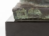 bronze statue of a dog on a black base with a white background