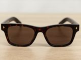 sunglasses on a wooden table with a white wall in the background