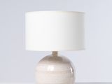 une lampe blanche posée sur une table, à côté d'une autre lampe blanche